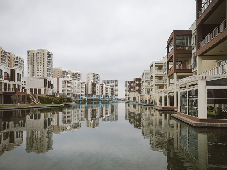 Modern residential buildings reflecting in a tranquil urban canal.